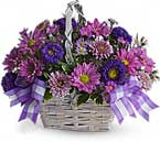 a white basket with rich purple and dark pink flowers inside and a purple checked ribbon