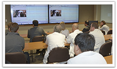 physicians watching a presentation on two screens in a conference room
