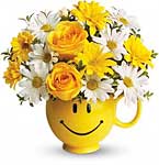 a bright yellow mug with a smiley face, with daisies and yellow roses inside