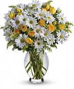 a large, cheerful white and yellow arrangement in a traditional glass vase