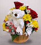 a country basket with white and yellow daisies, red roses, and a stuffed teddy bear