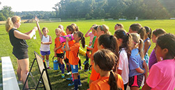 a group of young soccer players listening to their coach